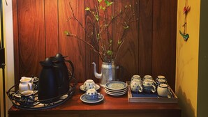 A wooden wall with a framed landscape painting, a vase with branches, and a tea set on a wooden table. - Öndólfsstaðir Farm B&B (Laugar)
