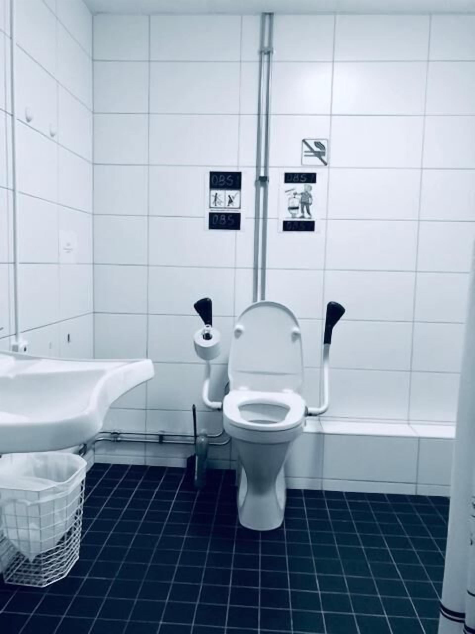 Ett litet, vitt badrum med en toalett, ett handfat och en papperskorg.