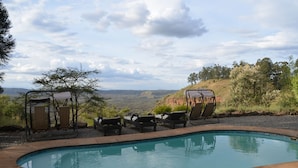 A swimming pool with lounge chairs and a view of a natural landscape. - Maili Saba Camp (Nakuru)