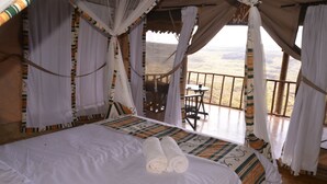 A bed with rolled towels, a table, and chairs in a room with a view. - Maili Saba Camp (Nakuru)