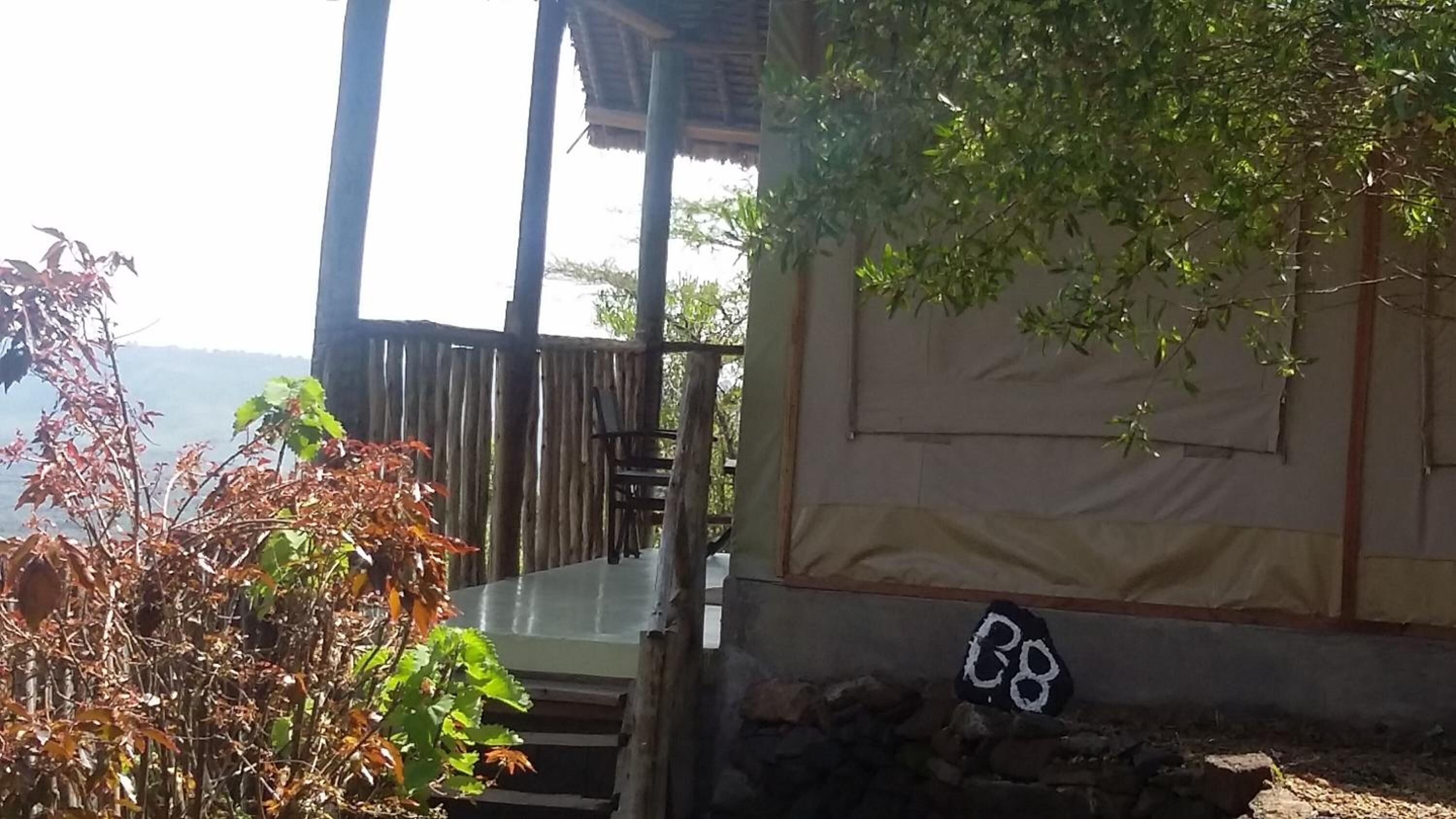 A rustic wooden structure with a table and chairs outside, overlooking a body of water.