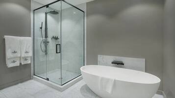 A modern bathroom with a glass-enclosed shower, a freestanding bathtub, and a marble-tiled floor.