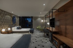 A modern hotel room with a large bed, a desk, a chair, and a TV.