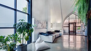 Ein modernes Interieur mit großen Fenstern, einem weißen Sofa und Topfpflanzen.