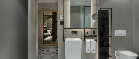 Un baño moderno con un lavamanos pedestal blanco, un estante negro y un inodoro blanco.