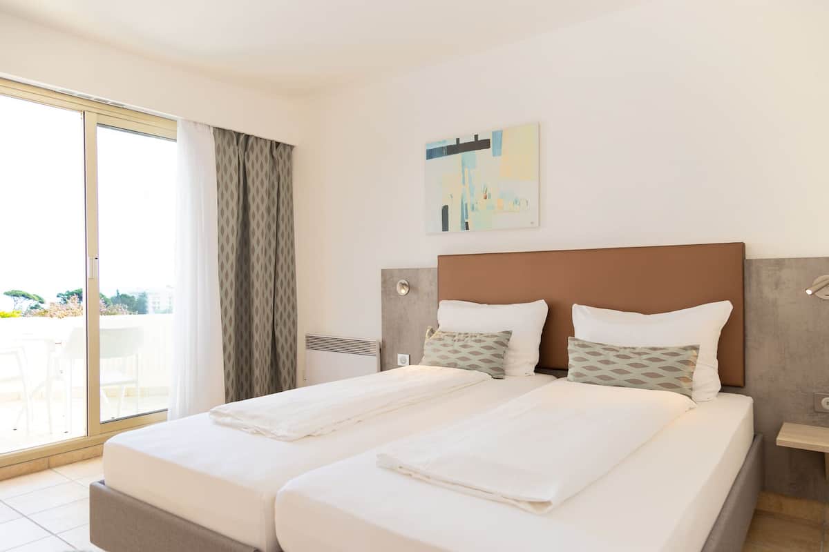 A double bed with two pillows, a headboard, and a wall-mounted artwork.