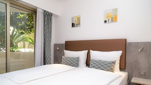 A neatly made bed with a brown headboard, two pillows, and a bedside table.