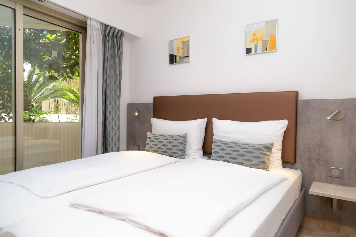 A neatly made bed with a brown headboard, two pillows, and a bedside table.
