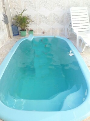 Una piscina al aire libre, sombrillas, sillones reclinables de piscina