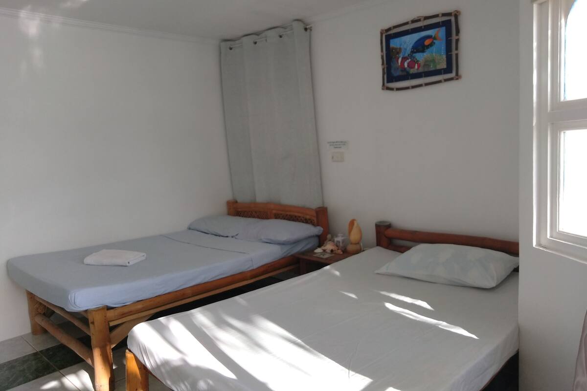 Ein Zimmer mit zwei Einzelbetten, einem Fenster und einem Wandbild.