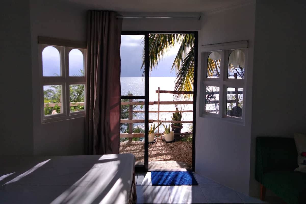 Ein Schlafzimmer mit Bett, Meerblick und einem Balkon mit Pflanzen.