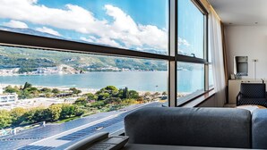 A hotel room with a large window offering a view of a lake, mountains, and a cityscape. - Hotel Harmonia by Dukley (Budva)