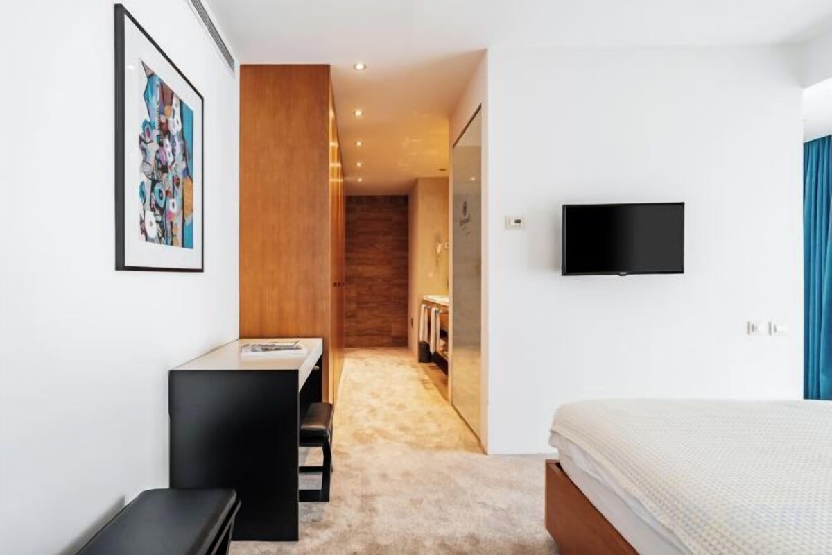 Un dormitorio moderno con cama, escritorio y televisor.