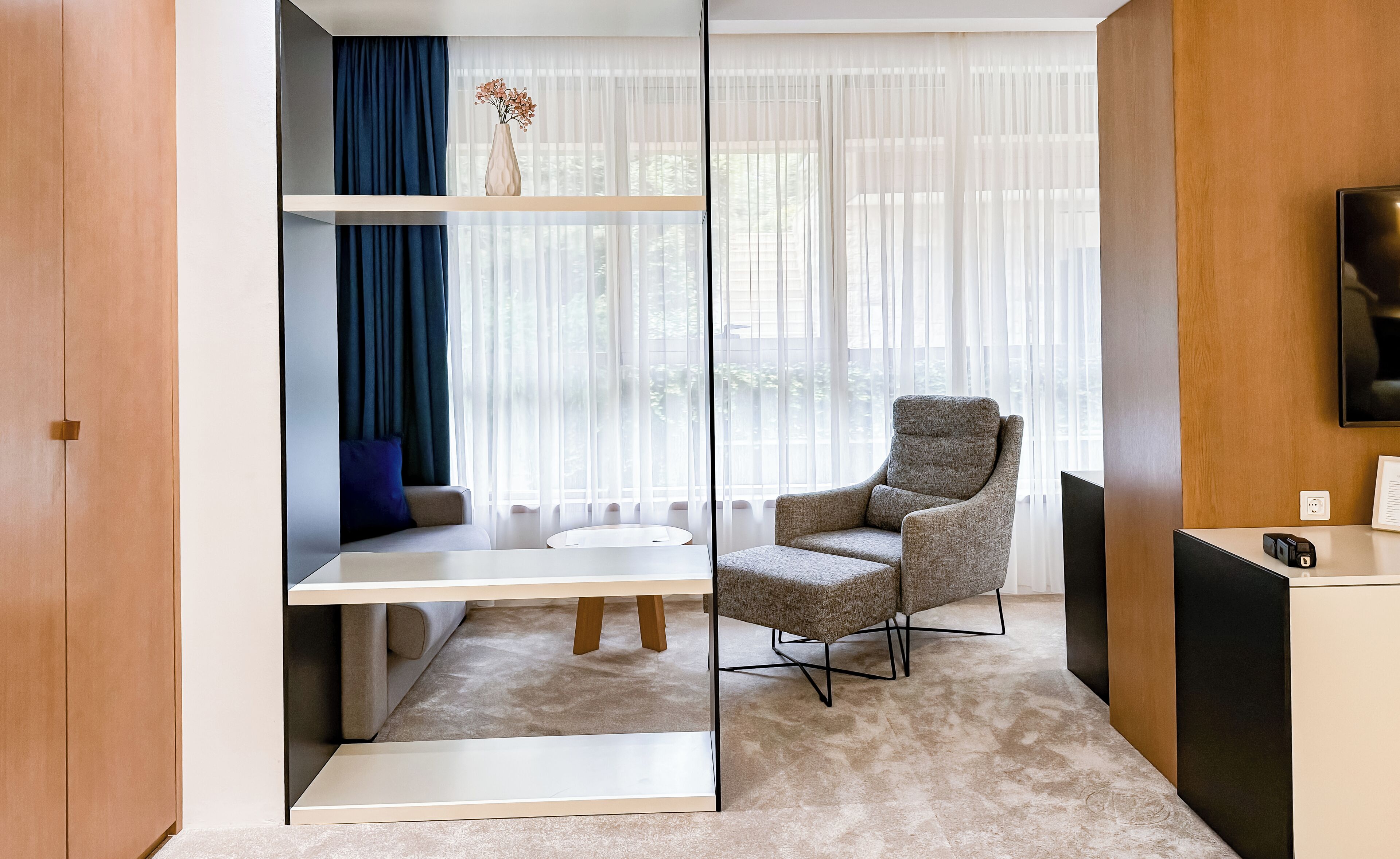 A modern room with a sofa, a chair, a small table, and a TV.