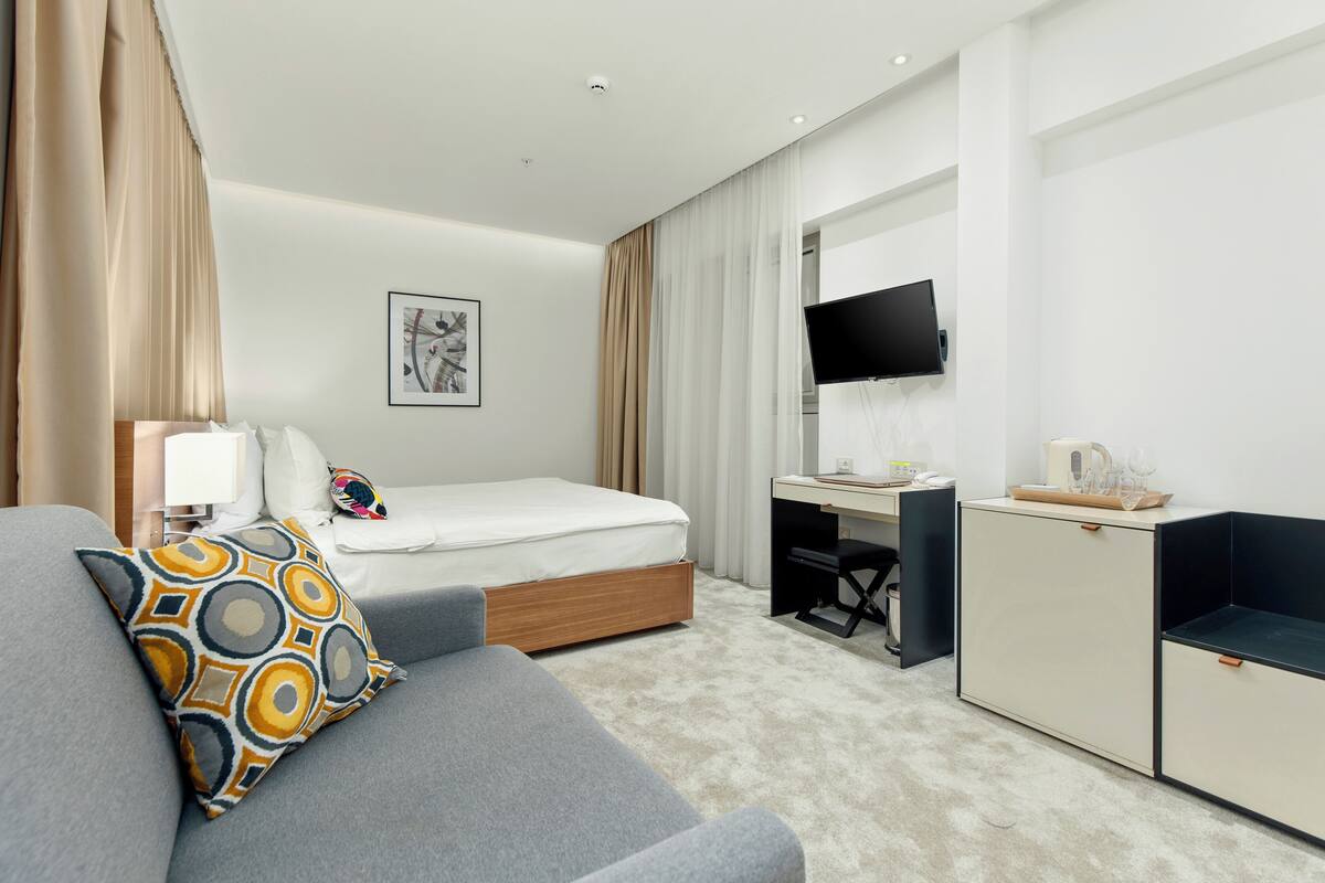 Ein Hotelzimmer mit Bett, Schreibtisch, Fernseher und einer Couch.