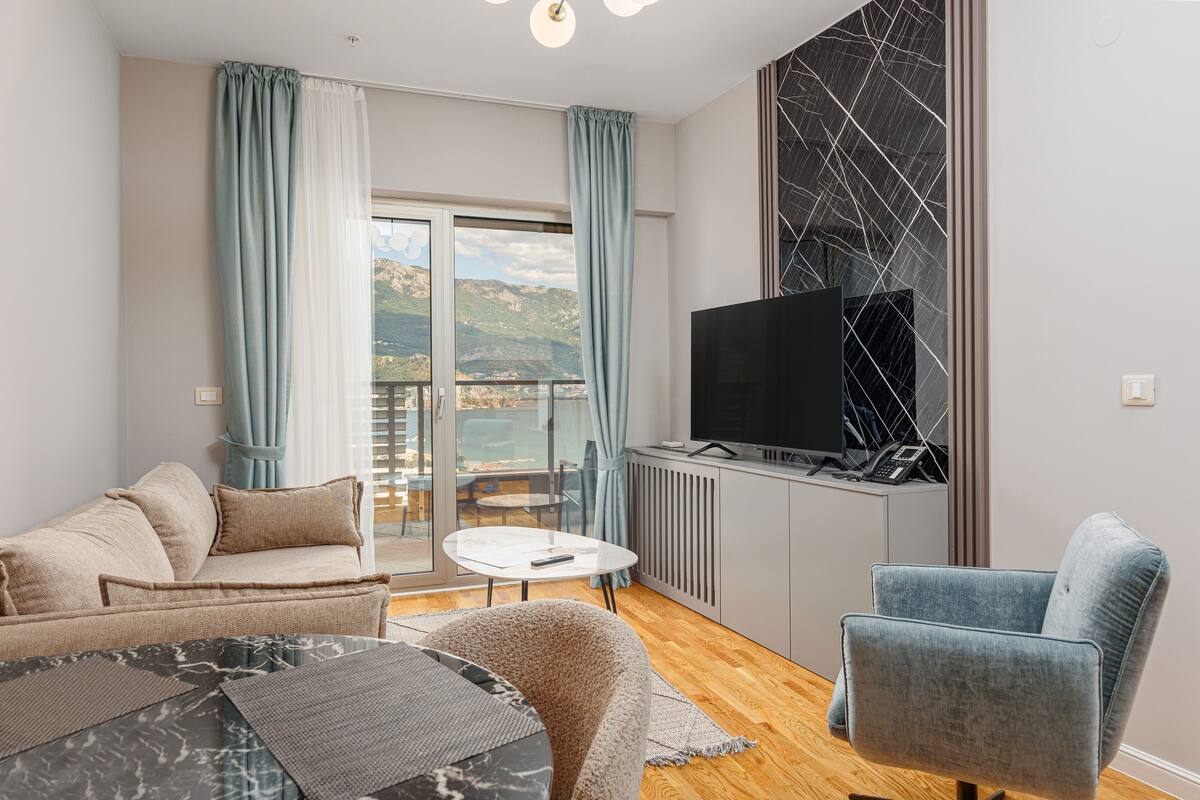 Ein modernes Wohnzimmer mit Sofa, Sessel und Fernseher auf einem Schrank.