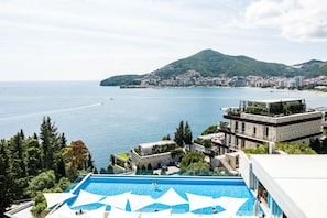 Un hôtel doté d’une piscine, offrant une vue sur la mer et avec une montagne en toile de fond.