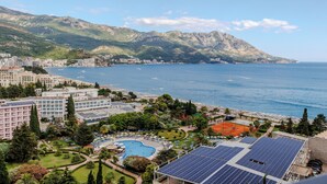 A coastal resort with a swimming pool, solar panels, and a view of the sea and mountains. - Hotel Harmonia by Dukley (Budva)