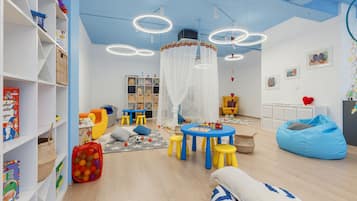 Children can play and learn in this vibrant playroom with a table, stools, bean bag chair, and playpen.