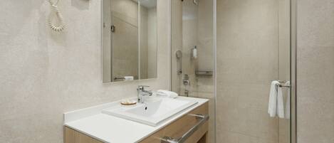 A modern bathroom with a double sink vanity, a glass shower enclosure, and a mounted hairdryer.