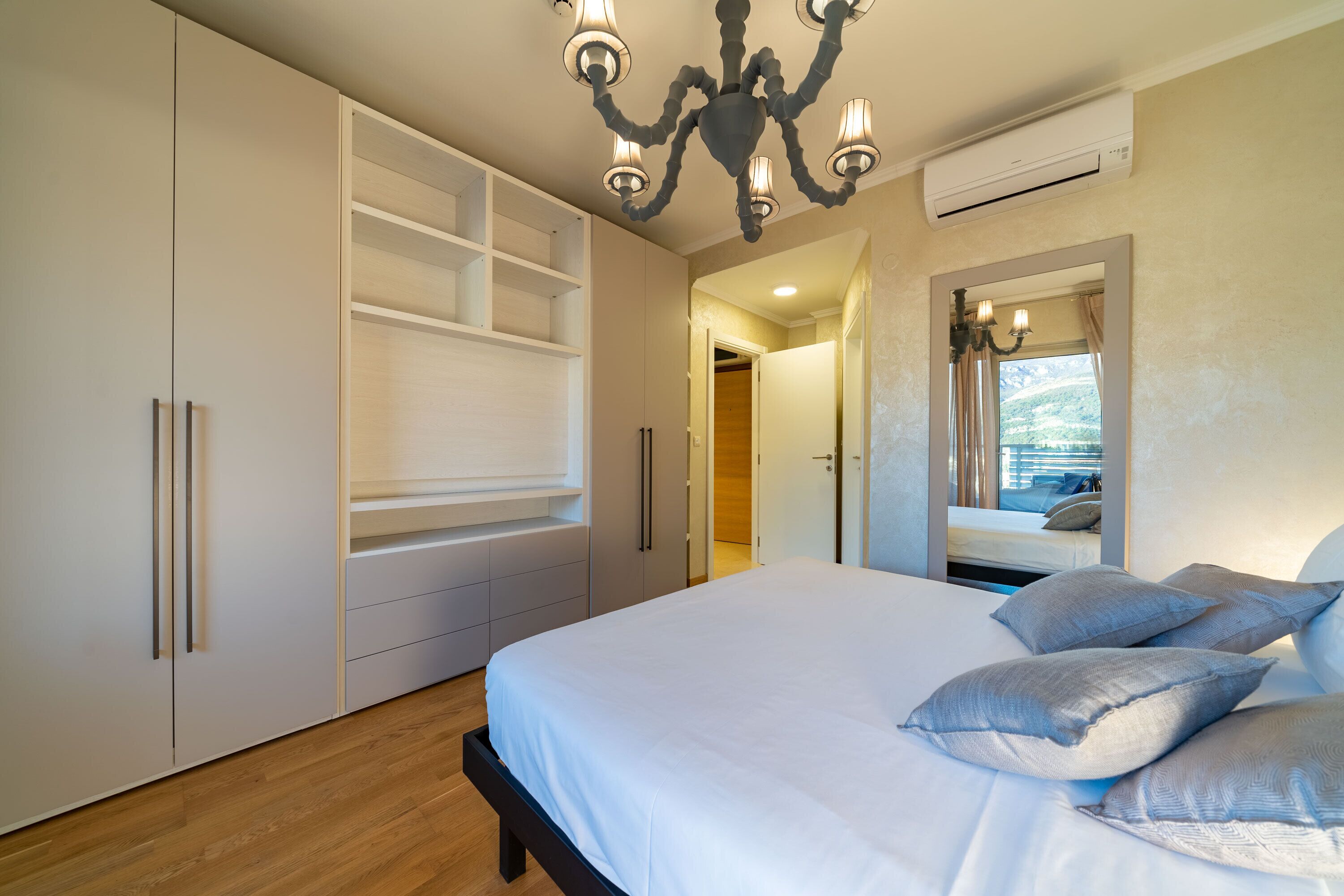 A bedroom with a bed, a wardrobe, and a mirror.