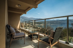 Un balcon avec vue sur les montagnes et un lac. On y trouve deux chaises et une table.