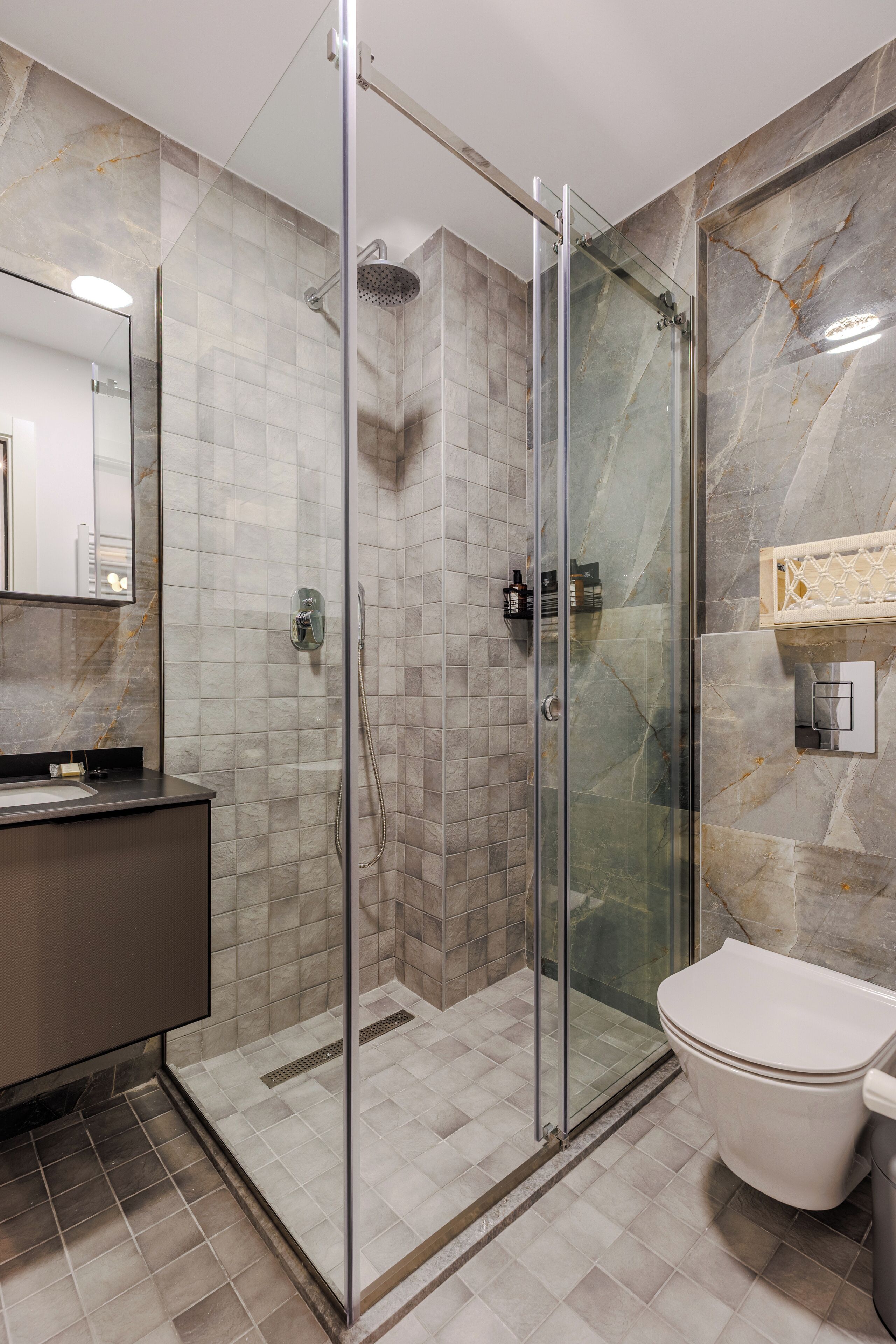Un baño moderno con ducha envuelta en vidrio, inodoro y tocador con espejo.