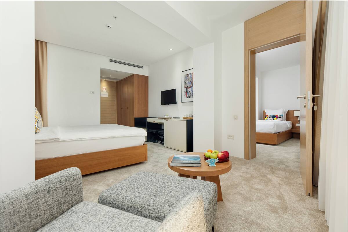 Ein modernes Hotelzimmer mit Bett, Schreibtisch, Fernseher und einer kleinen Sitzecke.