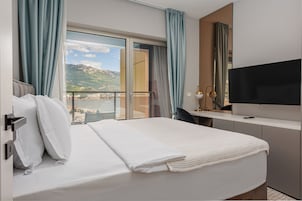 Habitación de hotel con cama, escritorio, televisor y vistas a las montañas.