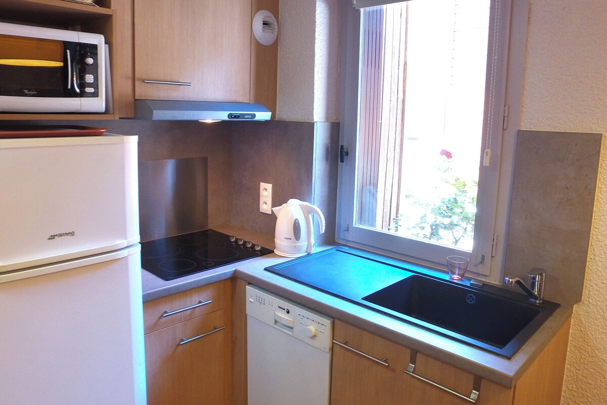 A compact kitchen with a refrigerator, microwave, stove, and sink.