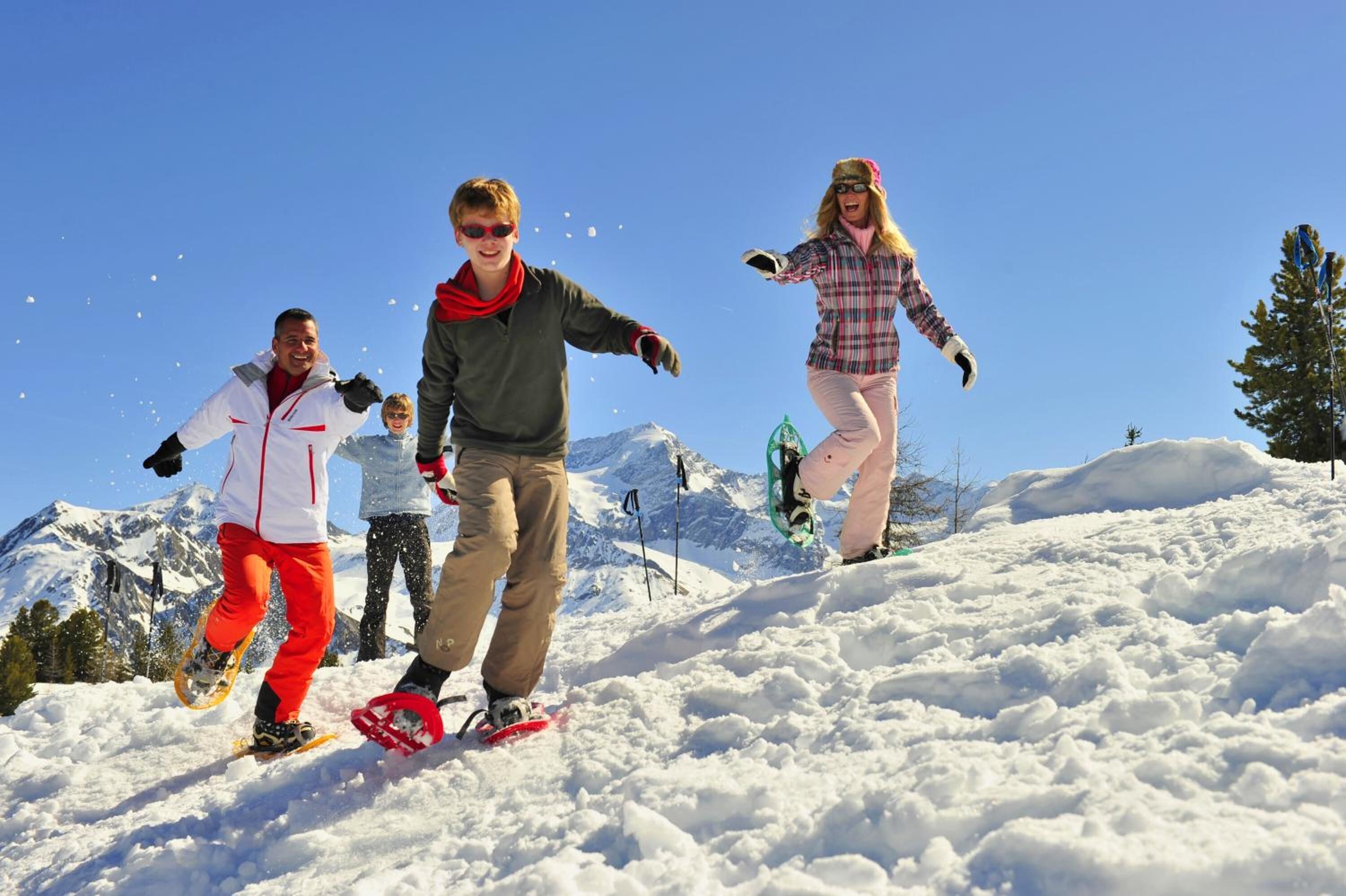 Eine Gruppe von Personen snowboardet auf einem verschneiten Berg bei klarem Himmel.