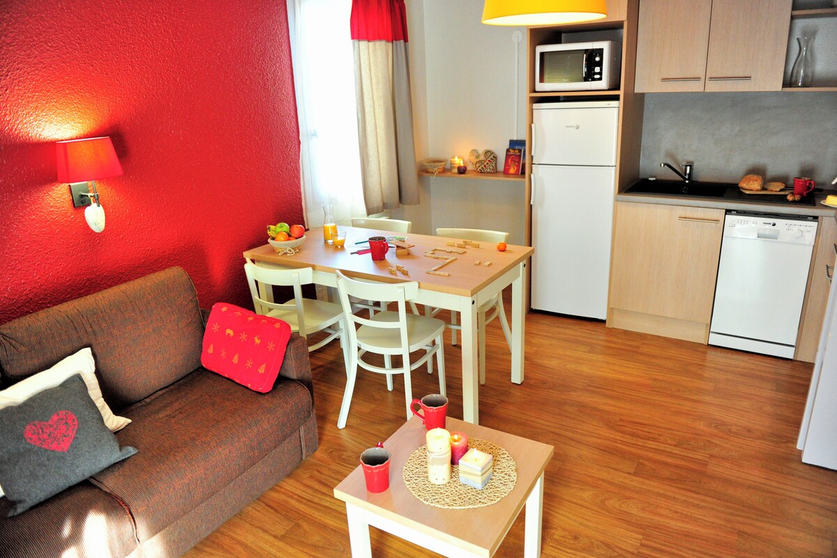 A compact living space with a dining area, kitchenette, and a red accent wall.