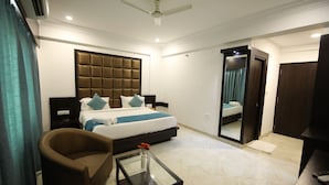 A hotel room with a bed, a sofa, a coffee table, and a mirror. - Hotel Bauji Palace (Udaipur)