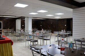 A spacious dining area with multiple tables and chairs, equipped with water bottles and cutlery.