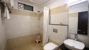 A small bathroom with a toilet, sink, shower, and towel rack. - Hotel Bauji Palace (Udaipur)