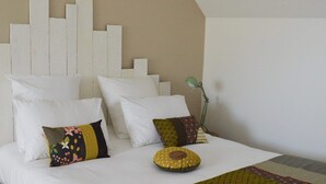 A neatly made bed with white bedding and multiple pillows, a green lamp on the bedside table, and a patterned throw blanket. - Mont Voyageur (Sains)