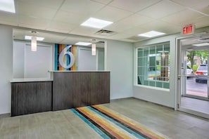 A reception area with a large number '6' sign, a reception desk, a striped carpet, and an exit sign.