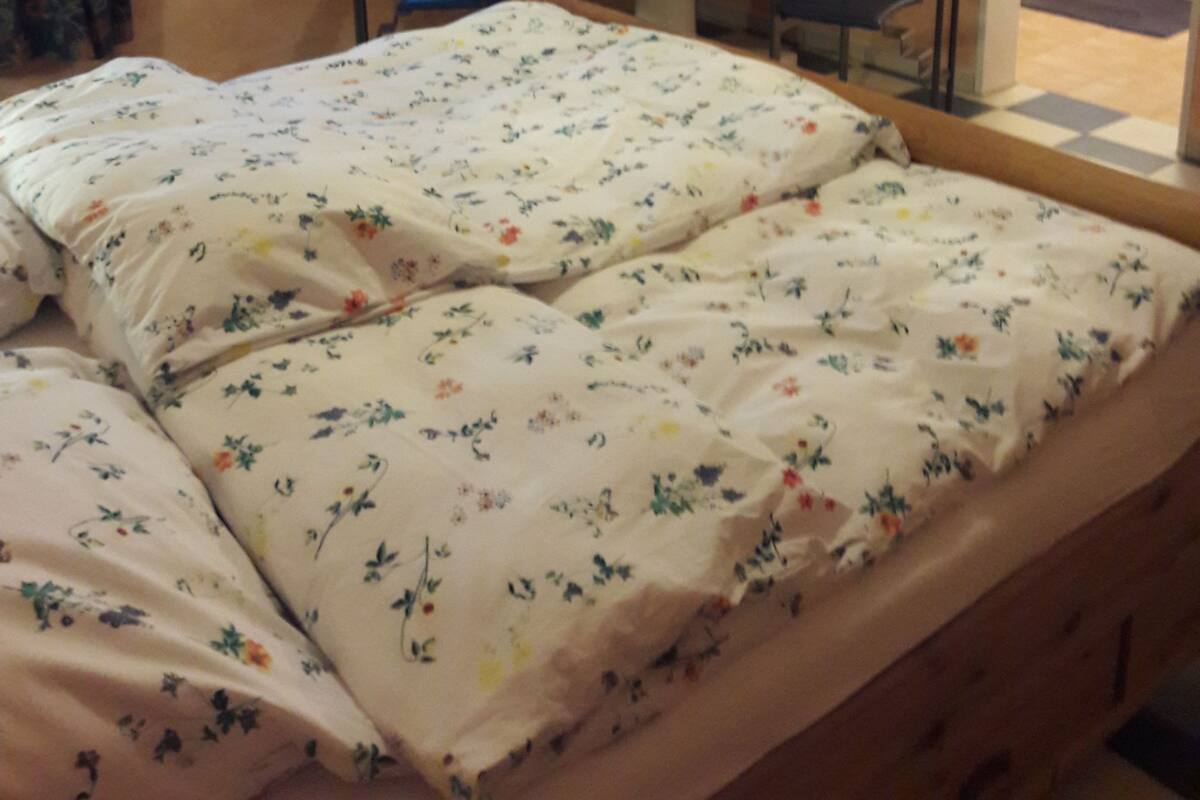 Quarto com cama, mesa redonda e janela com cortinas.