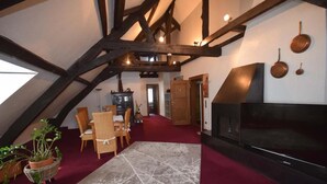 Una habitación estilo loft acogedora con zona de comedor, chimenea y televisor.