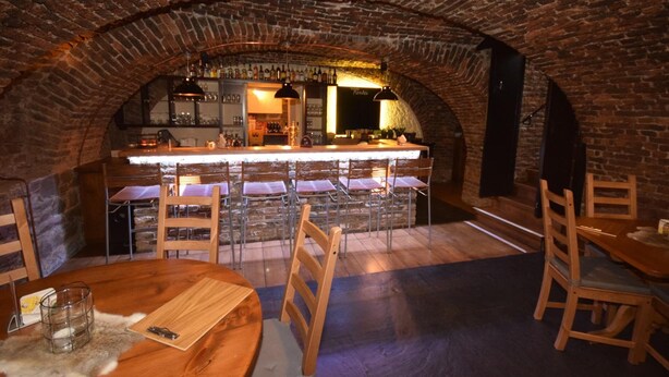 Un interior con un arco de ladrillo, una zona de bar con taburetes y una mesa de comedor con sillas.