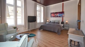 Un dormitorio moderno con una cama, televisión, escritorio y una silla.