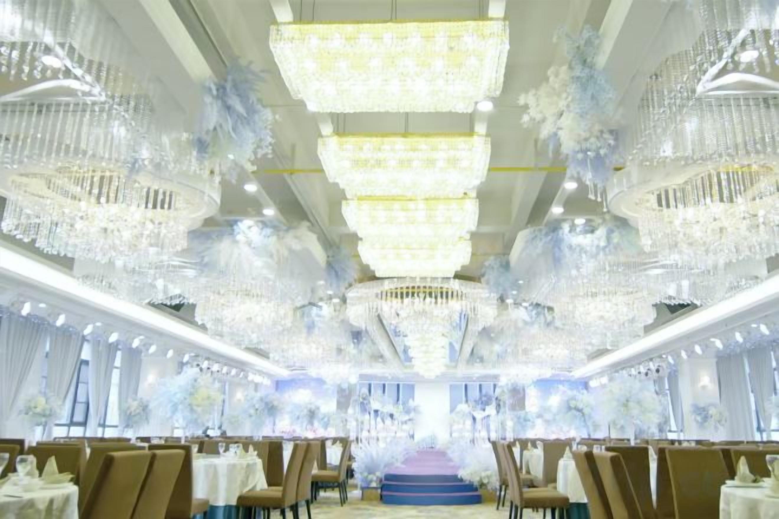 Un salón de banquetes con múltiples candelabros, mesas y sillas dispuestas para un evento formal.