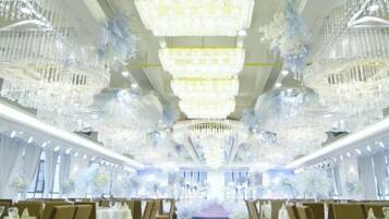 Un salón de banquetes con múltiples candelabros, mesas y sillas dispuestas para un evento formal.