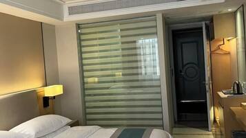 Ein Hotelzimmer mit einem Bett, einem Nachttisch mit Lampe, einer Schiebetür und einer kleinen Küchenzeile.