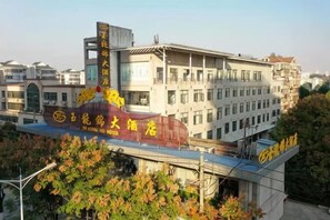 A hotel with a prominent sign, multiple floors, and a bridge connecting to another building. - Yu Long Jin Hotel (Ezhou)