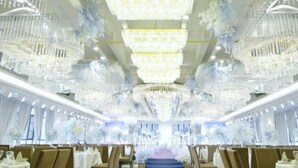A grand hall with multiple chandeliers, tiered seating, and floral decorations. - Yu Long Jin Hotel (Ezhou)