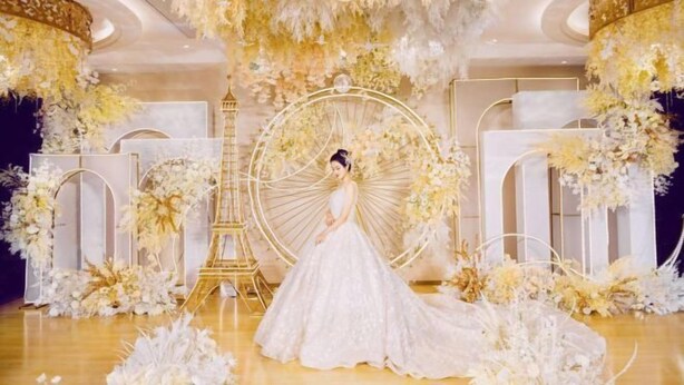 A wedding venue with a large decorative arch, a golden Eiffel Tower replica, and floral arrangements. - Yu Long Jin Hotel (Ezhou)