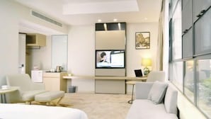 A hotel room with a bed, a sofa, a TV, a desk, and a window. - Yu Long Jin Hotel (Ezhou)