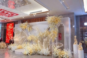 A hotel lobby with a decorative floral arrangement, a red sign with Chinese characters, and a modern light fixture. - Yu Long Jin Hotel (Ezhou)