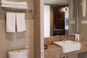 A bathroom with a toilet, a sink, a towel rack with towels, and a mirror. - Yu Long Jin Hotel (Ezhou)